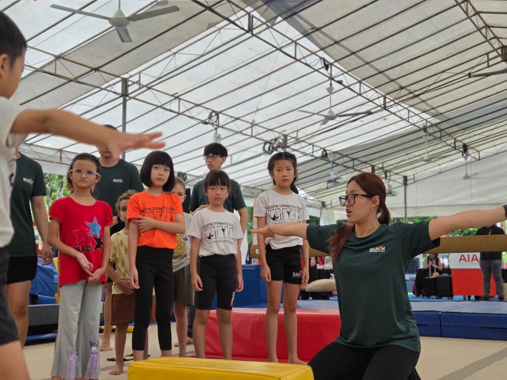 Instructor demonstrating a pose to a line of children